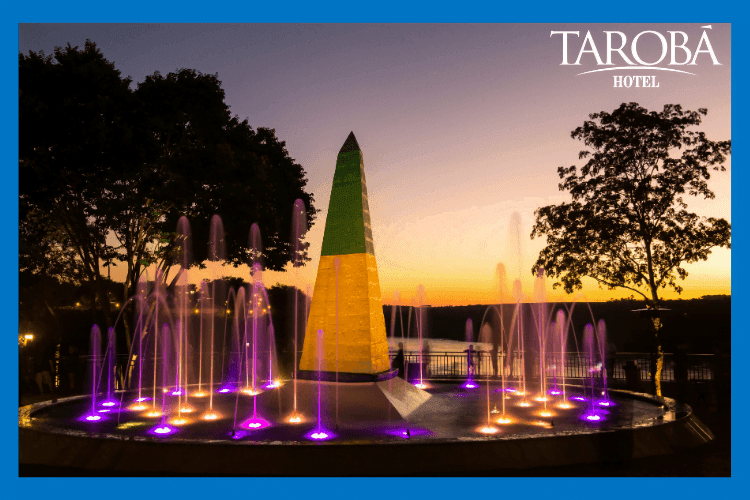 Fonte de que água, no Marco das Três Fronteiras, com as luzes acesas durante o pôr do sol. Passeios em Foz do Iguaçu dicas de passeios econômicos.